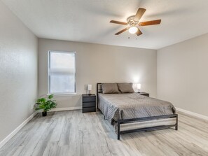 A bedroom with a bed, bedside tables, a ceiling fan, a window with blinds, and a potted plant. - Spacious 3-bedroom house in Tulsa, centrally located (Tulsa)