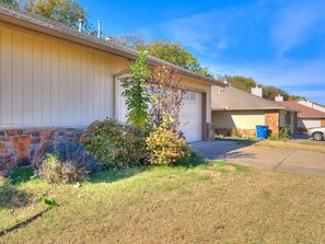 A residential house with a garage, stone foundation, and a driveway. - Spacious 3-bedroom house in Tulsa, centrally located (Tulsa)