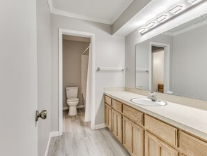 A modern bathroom with a wooden vanity, a large mirror, and a white toilet. - Spacious 3-bedroom house in Tulsa, centrally located (Tulsa)