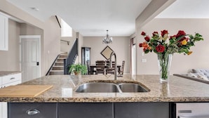 Ett modernt kök med bänkskivor i granit, diskhoar i rostfritt stål och svarta köksluckor.