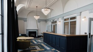 A spacious room with a large island counter, a fireplace, and elegant chandeliers. - Criterion Hotel Napier (Napier)