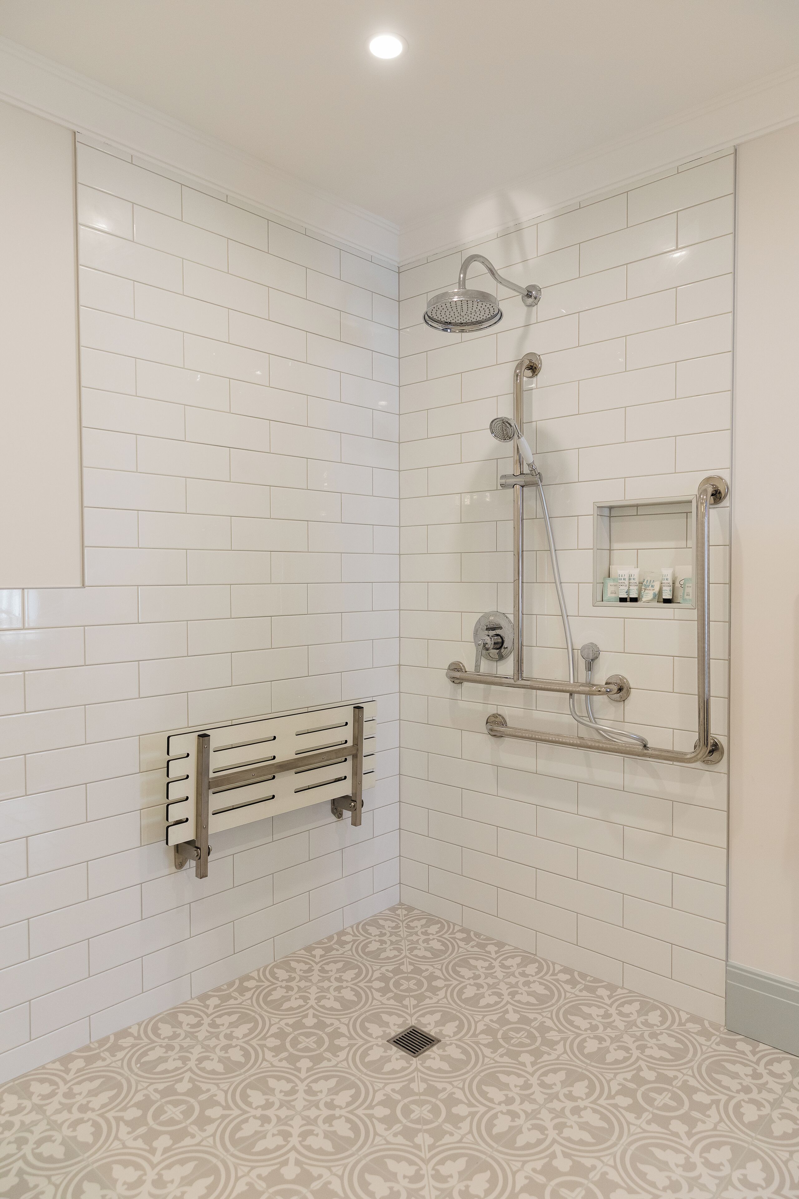 A modern bathroom with white subway tiles, a shower with a handheld showerhead, a handheld showerhead, and a handheld showerhead.