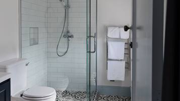Een moderne badkamer met een glazen douchecabine, een toilet en een vloer met een patroon.
