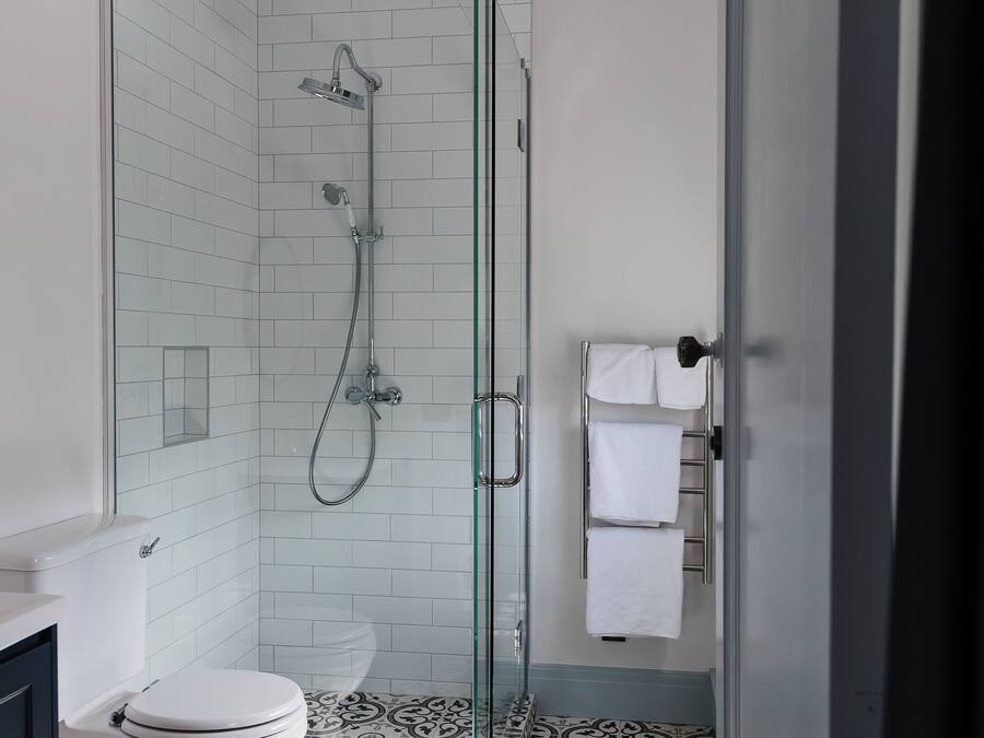 Een moderne badkamer met een glazen douchecabine, een toilet en een vloer met een patroon.