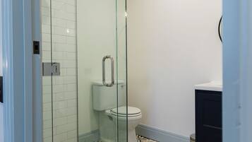Une salle de bain moderne avec une douche à parois de verre, des toilettes et des carreaux de sol à motifs.