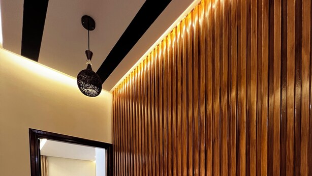 A hallway with a wooden wall, a potted plant with orange flowers, a bed in the background, and a ceiling light. - Belmar Martil - Chic and close to the sea (Martil)