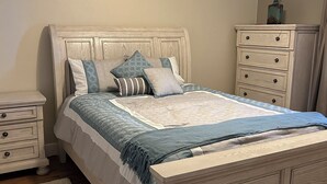 A bedroom with a bed, nightstands, a dresser, and a ceiling fan.