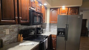 A kitchen with wooden cabinets, a stainless steel refrigerator, a microwave, an oven, and a coffee maker.
