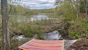 Un hamac est suspendu entre deux arbres, près d’une étendue d’eau.