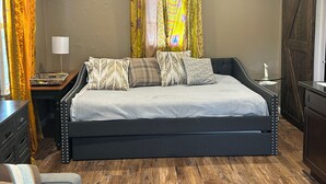 Une chambre à coucher avec un lit, des tables de chevet, une lampe et des rideaux.