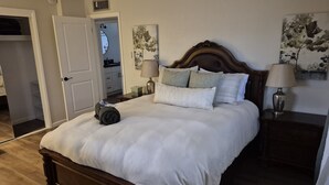 Ein ordentlich bezogenes Bett mit weißen Leinentüchern, einem hölzernen Kopfteil und zwei Nachttischlampen.
