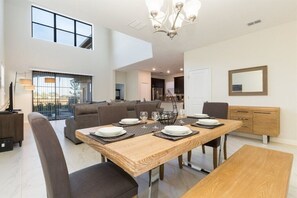 A modern dining area with a wooden table set for four, surrounded by dark chairs. - Solterra Resort, Elegant 5 bdrm home with Pvt pool (Davenport)