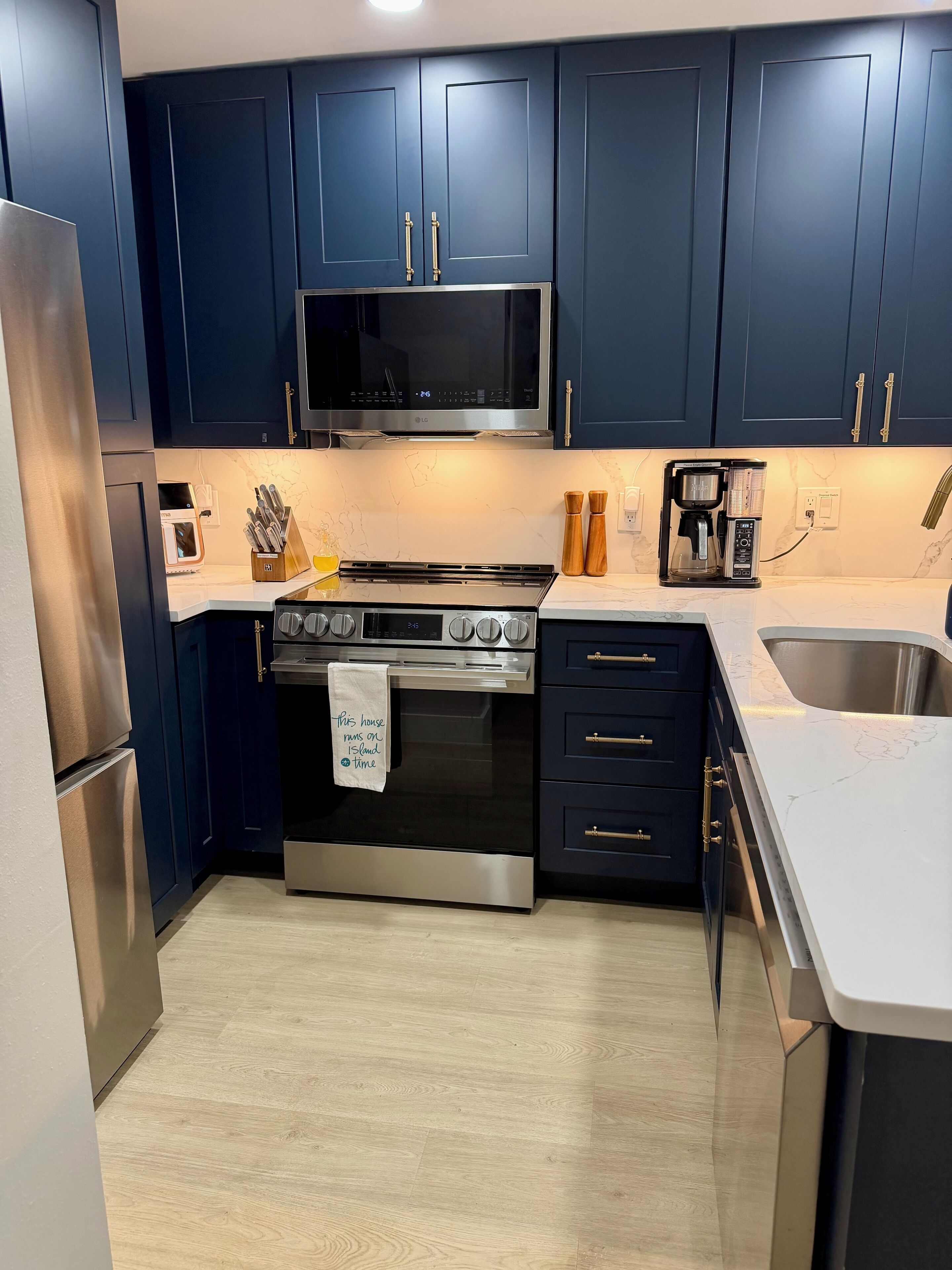 Una cocina moderna con armarios azul oscuro, electrodomésticos de acero inoxidable y encimera de mármol.