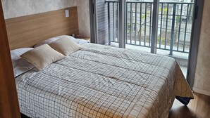 Een slaapkamer met een groot bed, een hoofdeinde, een raam met uitzicht en een ingelijst schilderij aan de muur.
