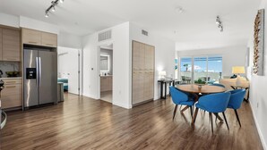 Eine moderne Küche mit Edelstahlkühlschrank, Holzschränken und einer Essecke mit blauen Stühlen und einem runden Tisch.