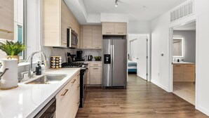 Eine moderne Küche mit Edelstahlgeräten, Holzschränken und einer weißen Arbeitsplatte.