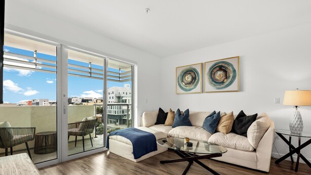 Ein modernes Wohnzimmer mit einer Couch, einem Couchtisch und Glastüren, die auf einen Balkon führen.