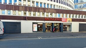 A modern building with a large storefront named 'Monoprix'. - Paris-Issy les moulineaux - Apartment the Queen (Issy-les-Moulineaux)