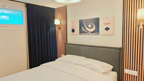 A hotel room with a bed, a TV, and artwork on the wall. - Paris-Issy les moulineaux - Apartment the Queen (Issy-les-Moulineaux)