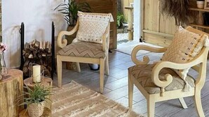 Un interior rústico de madera con dos sillones tapizados, un alfombrado tejido y un techo de madera.