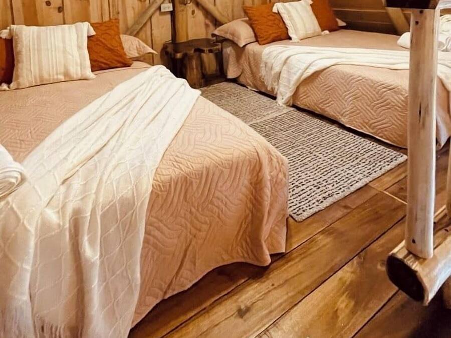 A cozy attic bedroom with two beds, wooden walls, and a sloped ceiling.
