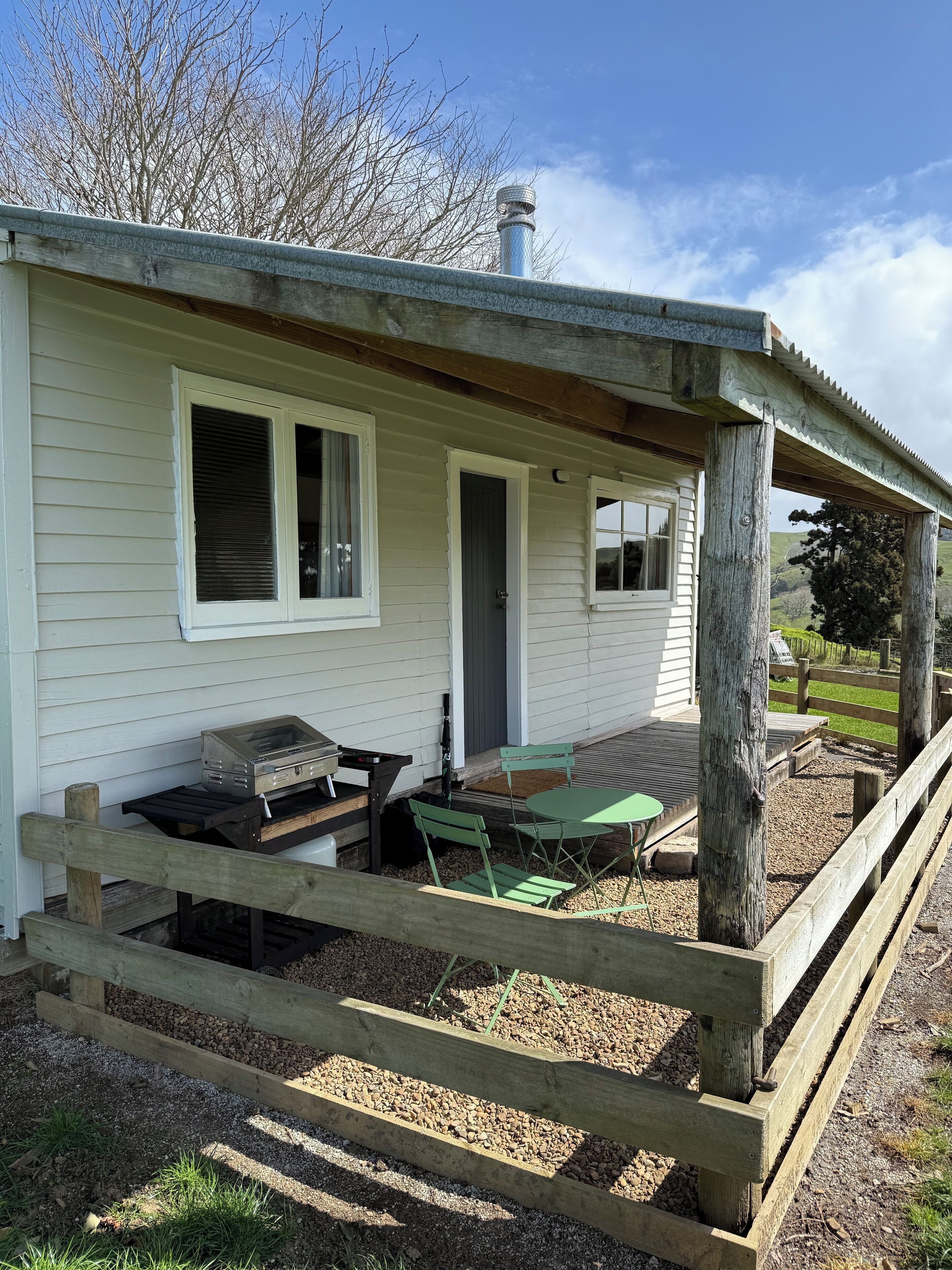 Une maison de plain-pied dotée d’un porche abrité, d’un barbecue et de meubles pour s’asseoir à l’extérieur.