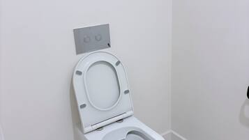 A white toilet with a closed lid in a bathroom with white walls and tiled floor.