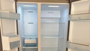 Un refrigerador abierto con varias estantes y un compartimento congelador.