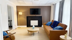 Una sala de estar moderna con un sofá, una mesa de centro y un televisor montado en la pared.