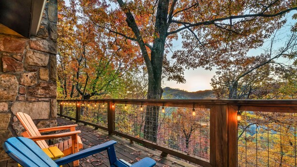 Un patio in legno con poltrone Adirondack e un muro in pietra.