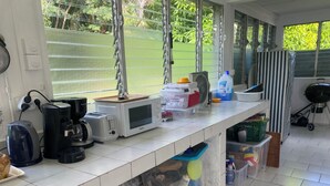 Una cocina con encimera blanca, electrodomésticos varios y recipientes de almacenamiento.