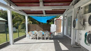 Un espacio de patio cubierto con mesa y sillas, unidades de aire acondicionado y un toldo azul.