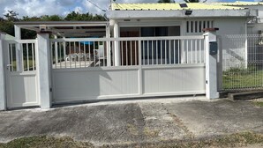 Propiedad residencial cerrada con antena parabólica, techo amarillo y valla blanca.