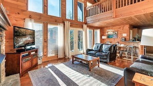 A spacious wooden cabin with a large living area, a television, a fireplace, and a balcony. - Free Dollywood Tickets, Sauna, Hot Tub, Secluded Modern Cabin, Dogs OK (Sevierville)
