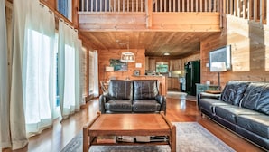 A wooden interior with a sofa, a coffee table, and a staircase leading to an upper level. - Free Dollywood Tickets, Sauna, Hot Tub, Secluded Modern Cabin, Dogs OK (Sevierville)