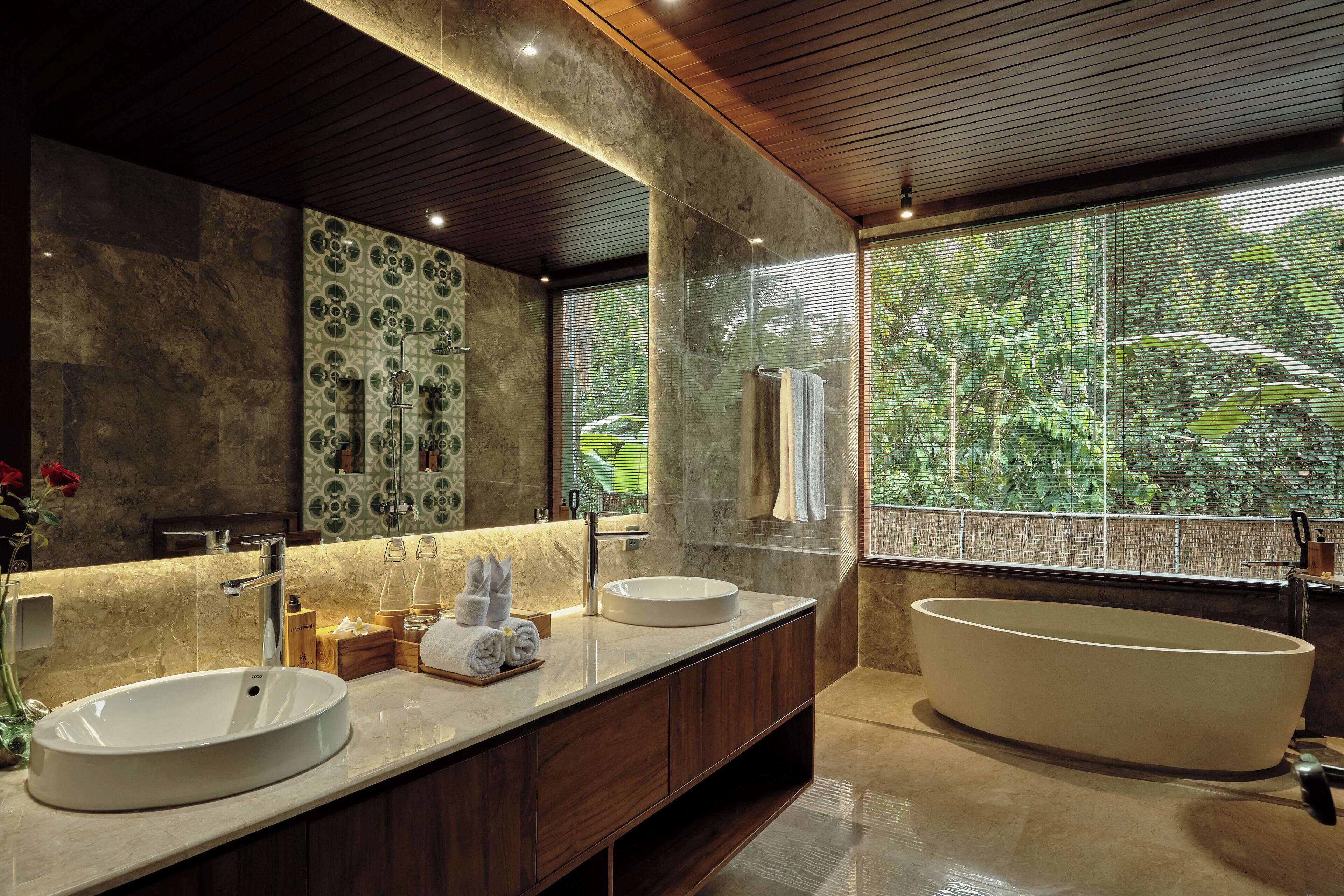 Un baño moderno con dos lavamanos, una bañera grande y un espejo amplio.