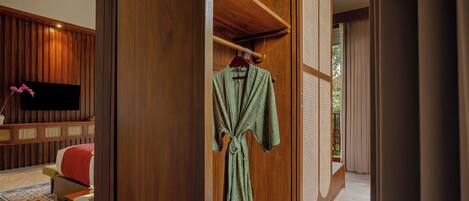 A room with a wooden wardrobe, a TV, a bed, and a window with curtains.