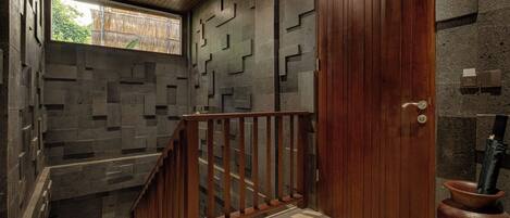 A staircase with a wooden railing, a wooden door, and a stone wall with geometric patterns.