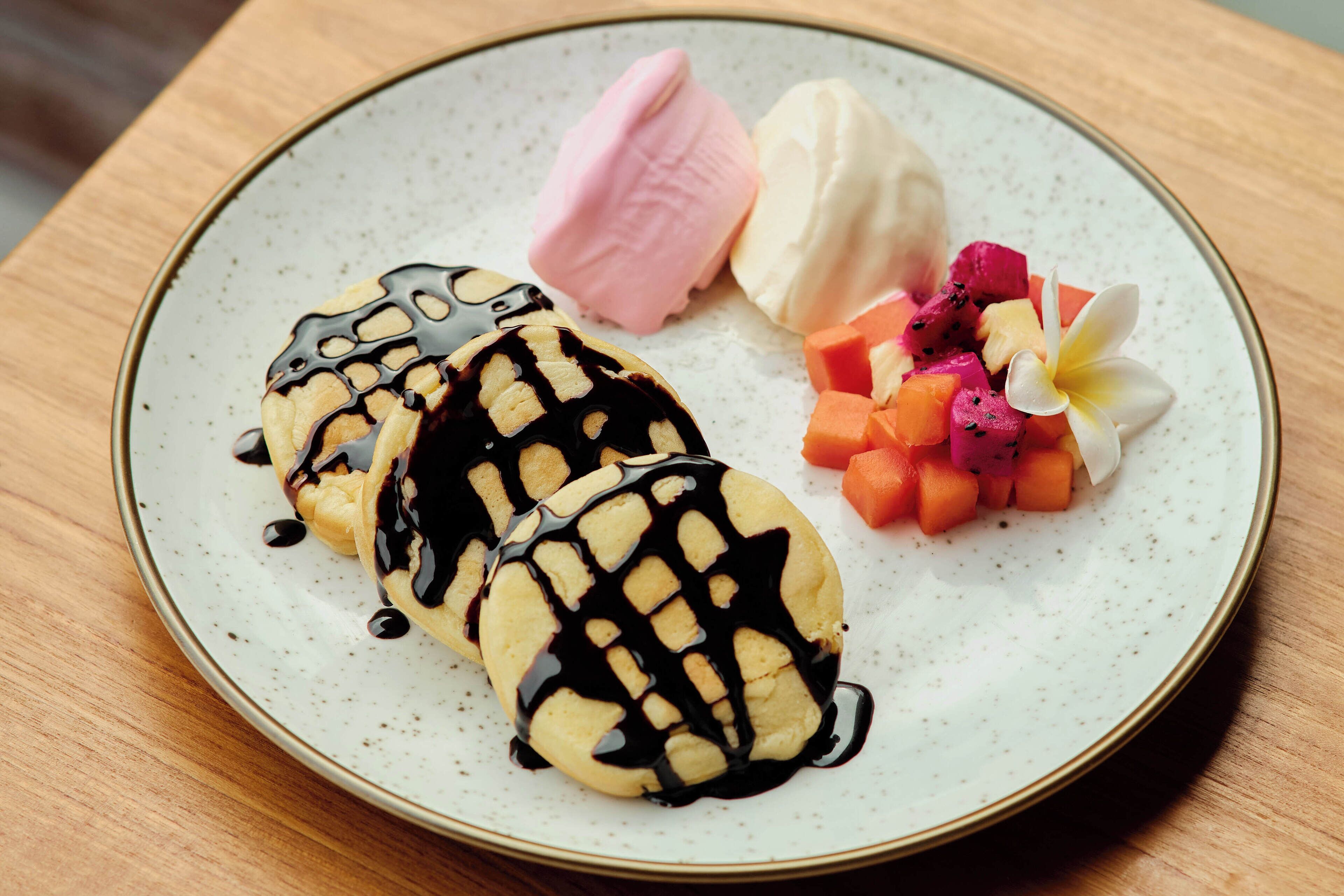 A dessert plate with waffles, ice cream, and fruit on a ceramic plate.
