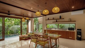 A modern kitchen with a wooden countertop, a built-in sink, and a large window overlooking greenery. - Nauma Ubud Villa (Ubud)