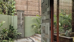 A small, enclosed garden area with a concrete shower, steps leading to a raised platform, and various plants. - Nauma Ubud Villa (Ubud)
