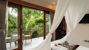 A bedroom with a large sliding glass door leading to a balcony with a view of lush greenery. - Orchid Ubud Cottage (Ubud)