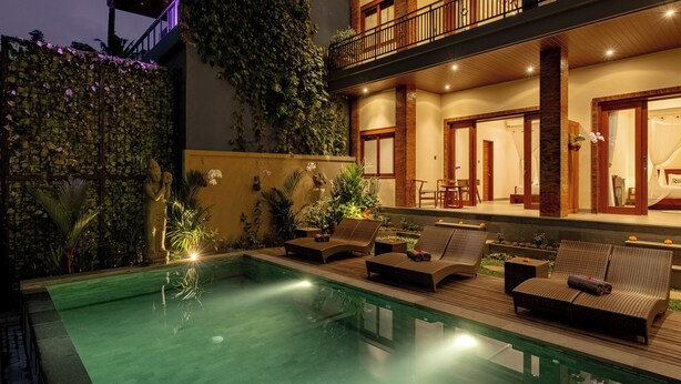 A pool area with lounge chairs and a well-lit balcony. - Orchid Ubud Cottage (Ubud)