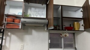 A kitchen with open cabinets, a stove, and various kitchenware.
