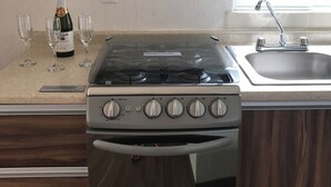 A kitchen with a stove, sink, and wine glasses.