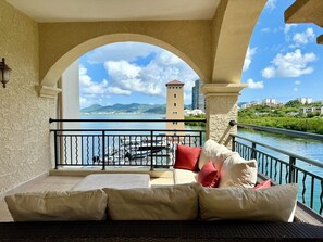 Un balcon avec vue sur une rivière, une tour et des montagnes.