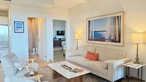 A modern living room with a sofa, armchairs, a coffee table, and a TV in the background. - NEW ! Elegant and modern 2-Bedroom, with marina and garden view in Porto Cupecoy (Sint Maarten)