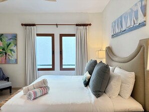 A hotel room with a large bed, a headboard, and a painting of sailboats on the wall. - NEW ! Elegant and modern 2-Bedroom, with marina and garden view in Porto Cupecoy (Sint Maarten)