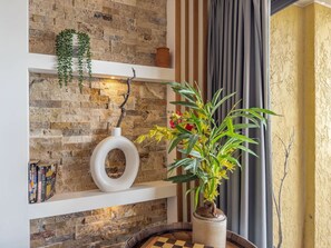 A room with a brick wall, a white shelf with books, a white vase, and a potted plant. - Caravelle 937 (Myrtle Beach)