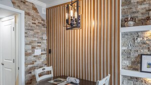 Ein Essbereich mit einem runden Tisch, weißen Stühlen, einer Wand aus Holzlatten und einer Steinwand mit Dekoration.